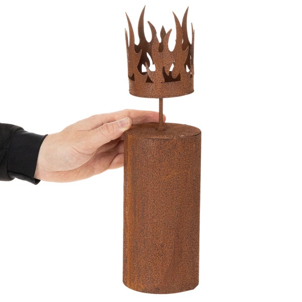 Garten-Dekoobjekt aus Metall in Edelrost-Optik mit Flammenaufsatz und Zylindersockel, Hand zum Größenvergleich.