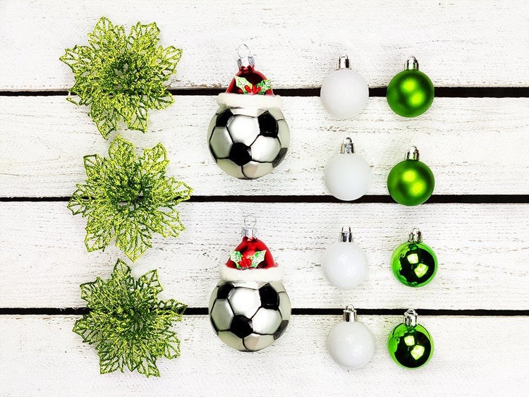 Weihnachtsbaumschmuck Set mit zwei Fußball Weihnachtskugeln mit Weihnachtsmannmütze, kleinen Kugeln und dekorativen grünen Blütenelementen.