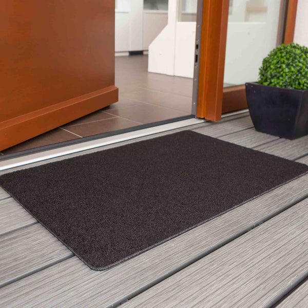 Schmutzfangmatte vor einer geöffneten Tür auf einem Terrassenboden