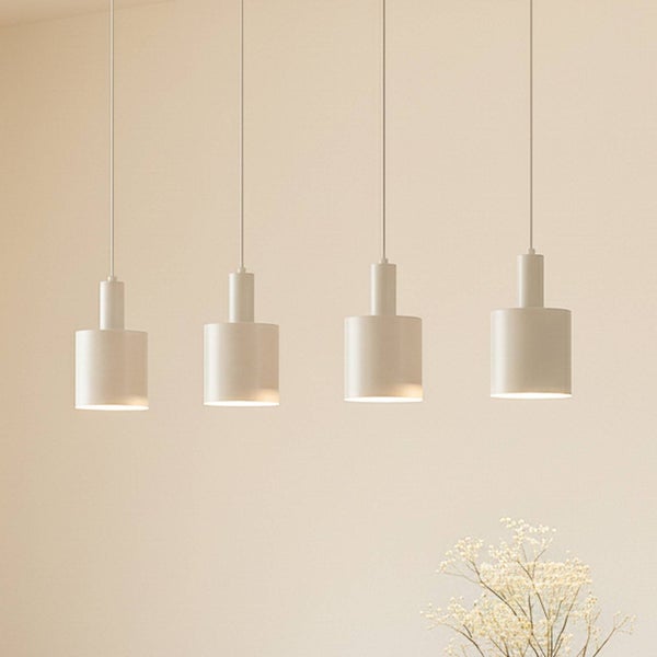 Vier zylindrische Pendelleuchten aus Metall über einem Tisch