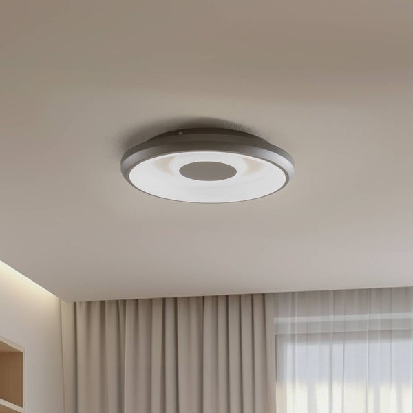Moderne runde LED-Deckenleuchte in Ringform an einer Zimmerdecke in einem hellen und organisierten Raum mit Vorhängen.