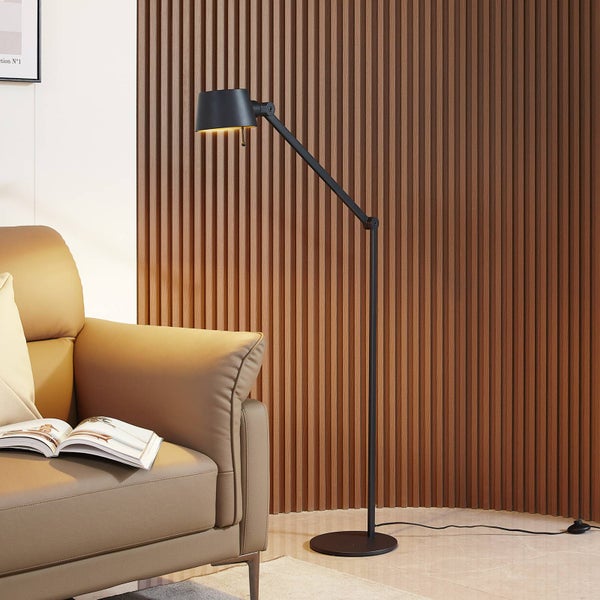 Moderne schwarze Stehleuchte mit verstellbarem Arm neben einem Sessel vor einer Wand mit Holzlatten.