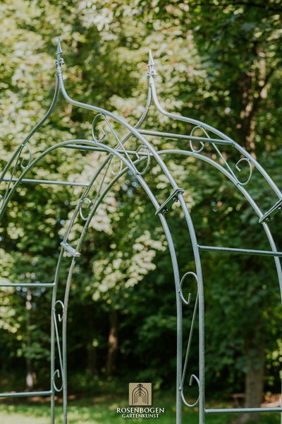 Detailansicht eines Rosenbogens aus Metall im Garten