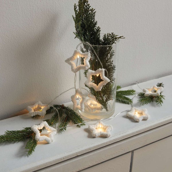 Dekoration mit Sternenlichterkette und Tannenzweigen in Vase