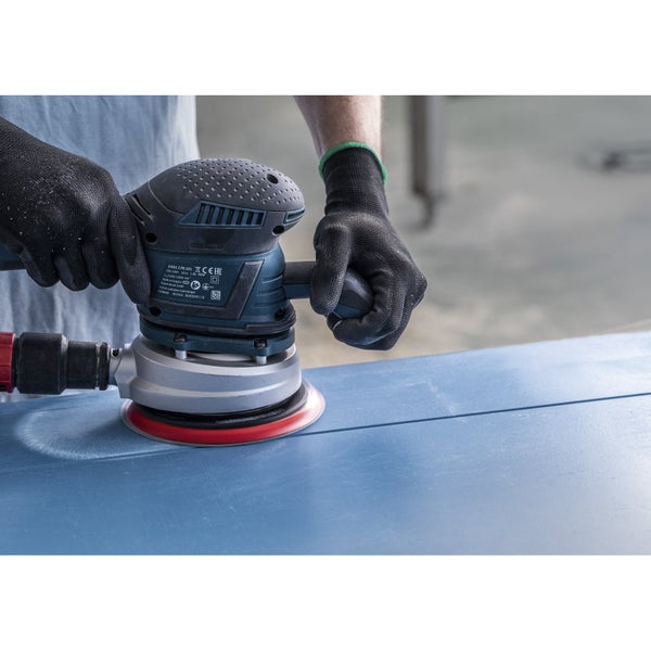 Ein Mann schleift mit einer Exzenterschleifmaschine ein blaues Brett