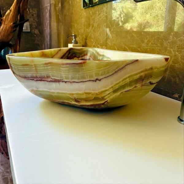 Helles Badezimmer mit Marmorwand und einem rechteckigen Aufsatzwaschbecken aus Onyx-Naturstein auf einer Waschtischplatte.