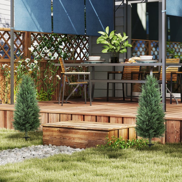 Moderne Holzterrasse mit Sitzgruppe, blauen Sonnenschutz-Rollos, kleinen Nadelbäumen und einem Holzzaun mit Rankgitter im Hintergrund.