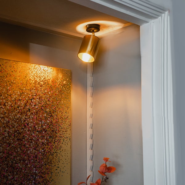 Messingfarbene Deckenleuchte mit Kunstwerk an der Wand