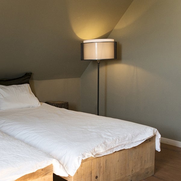 Schlafzimmer mit Doppelbett aus Holz und Stehlampe