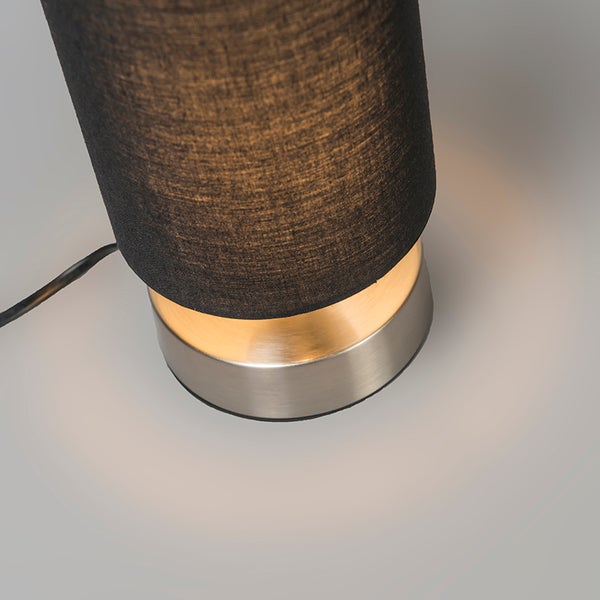 Nahaufnahme einer Tischleuchte mit schwarzem Stoffschirm und Metallsockel