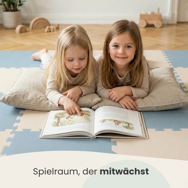 Zwei Kinder liegen auf Kissen auf einer Puzzlematte und lesen ein Buch in einem hellen, organisierten Spielzimmer.