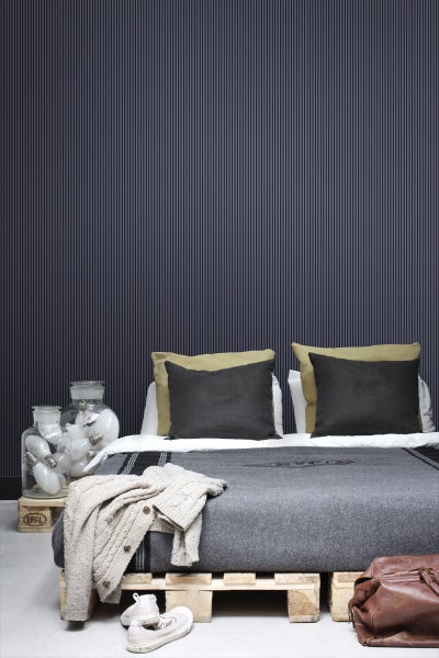 Schlafzimmer mit gestreifter Tapete, Bett auf Europaletten und Dekoration