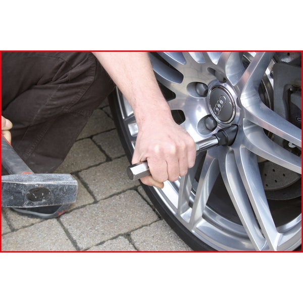 Radwechsel am Auto mit Hammer und Radkreuz
