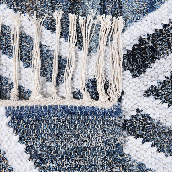 Nahaufnahme eines gewebten Teppichs mit Denim-Muster und hellen Fransen.