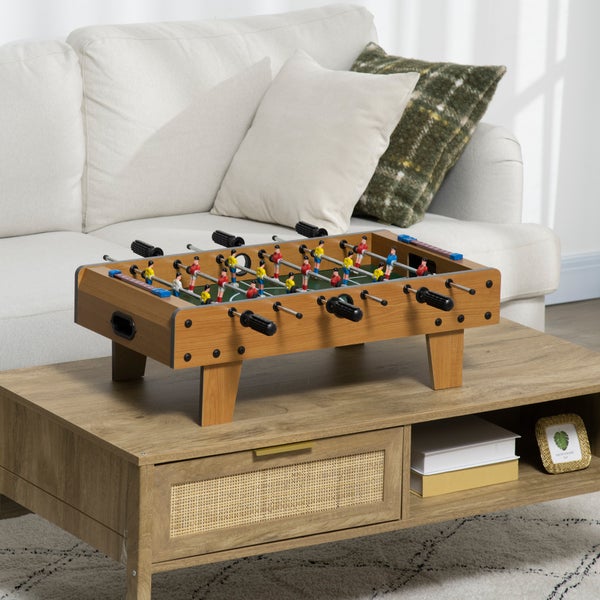 Tischfußballspiel aus Holz auf einem Couchtisch in einem hellen, organisierten Wohnzimmer mit Sofa.