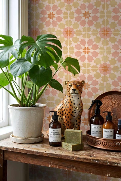Helle Dekoration mit Monstera-Pflanze, Leopardenfigur und Pflegeprodukten vor einer Wand mit geometrisch gemusterten Fliesen.