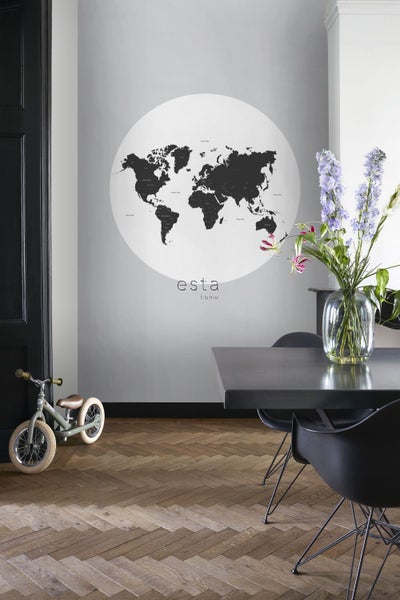 Szene eines Esszimmers mit einer Weltkarten-Tapete der Marke Esta Home, einem Tisch, Stühlen und einem Kinderfahrrad.