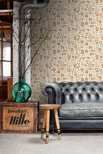 Wohnszene mit einer grauen Couch, einem Holzhocker, einer Holzkiste und einer Wandtapete mit Sportmotiven