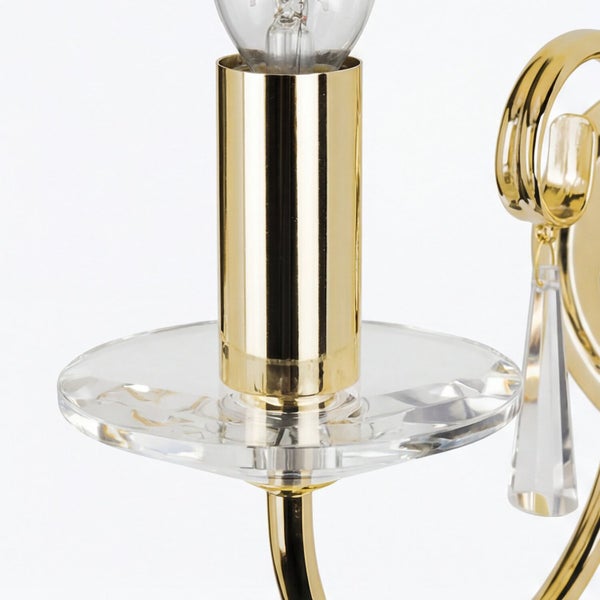 Detailaufnahme einer goldenen Wandleuchte mit Glühbirne und Kristallanhänger.