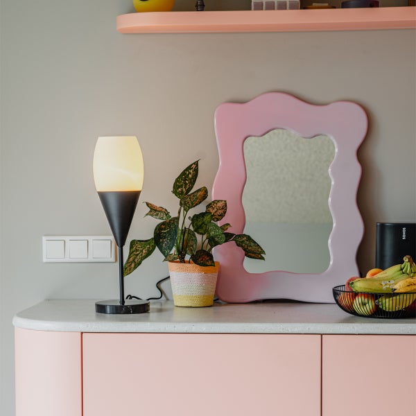 Dekorative Anordnung mit Lampe, Pflanze, Spiegel und Obstschale auf einer Kommode