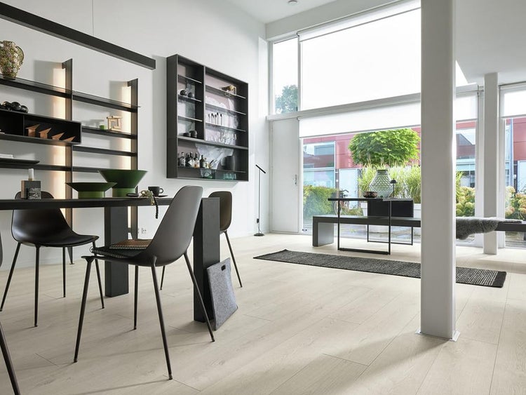 Helles Wohnzimmer mit Laminatboden in Holzoptik, moderner Einrichtung, großem Fenster und offener Gestaltung für eine wohnliche Atmosphäre.
