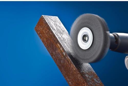 Drahtbürste beim Reinigen eines Metallstücks