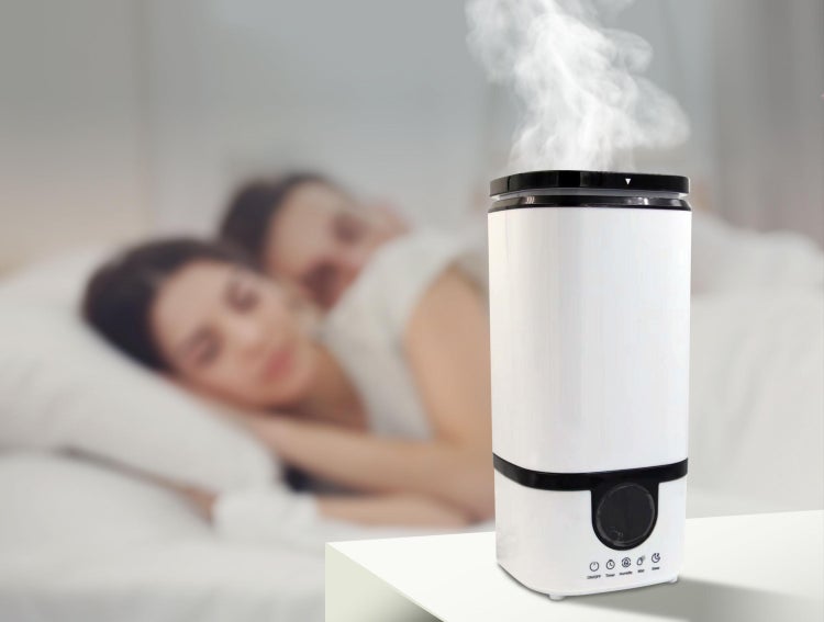 Luftbefeuchter im Schlafzimmer mit schlafendem Paar im Hintergrund