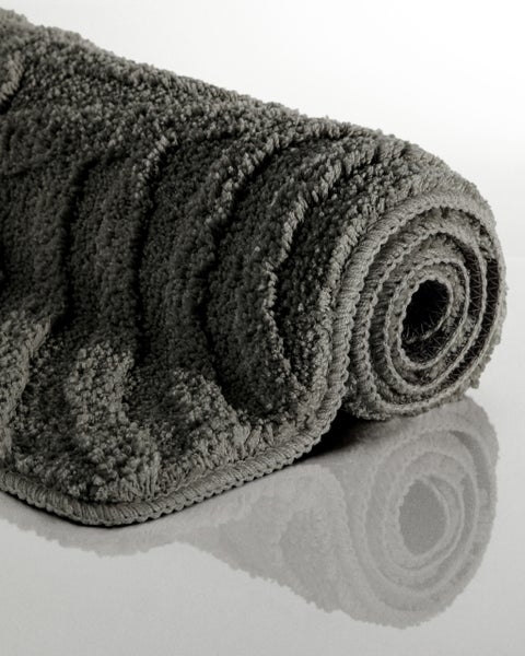 Gerollte flauschige Badematte mit strukturierter Oberfläche in Grau