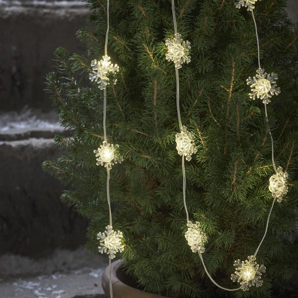 Dekorativer Lichterkette mit Schneeflocken um einen kleinen Baum gewickelt.