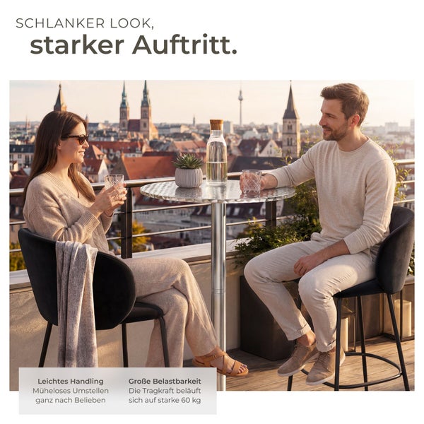 Mann und Frau an einem runden silbernen Stehtisch auf einem hellen Balkon mit Stadtblick. Sie sitzen auf dunklen Barhockern mit Lehnen.