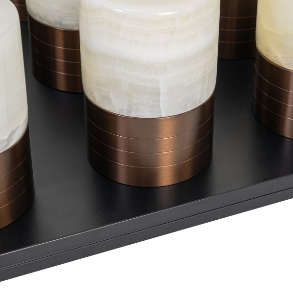 Detailansicht von zylindrischen Lampen mit weiß marmorierten Schirmen und bronzefarbenen Metallsockeln mit Rillen.