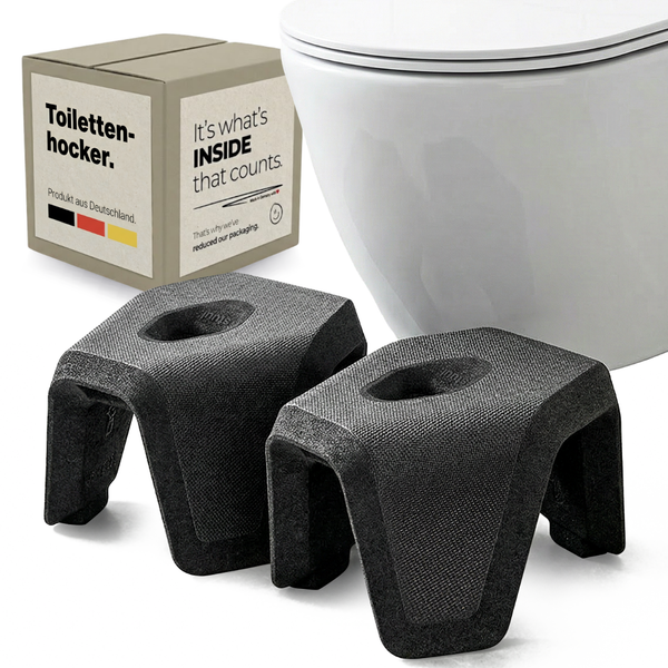 Zweiteiliger Toilettenhocker mit strukturierter Oberfläche in Grau vor einer weißen Toilette und dem Produktkarton.