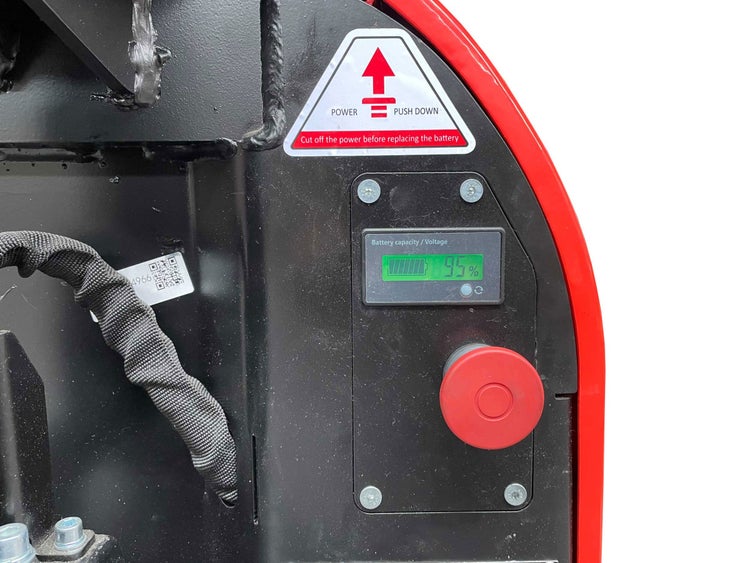 Detailansicht der Batterieanzeige eines Geräts mit Not-Aus-Schalter und Sicherheitshinweis