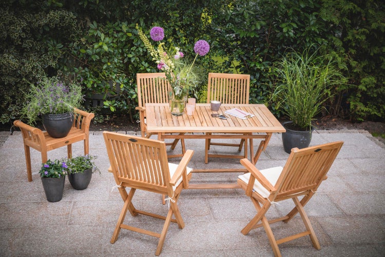 Gartenszene mit Holztisch und Stühlen auf einer Terrasse mit Pflanzen