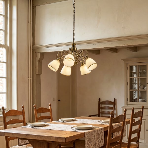 Rustikaler Essbereich mit einem antik wirkenden Kronleuchter mit fünf gläsernen Lampenschirmen über einem massiven Holztisch mit Stühlen.