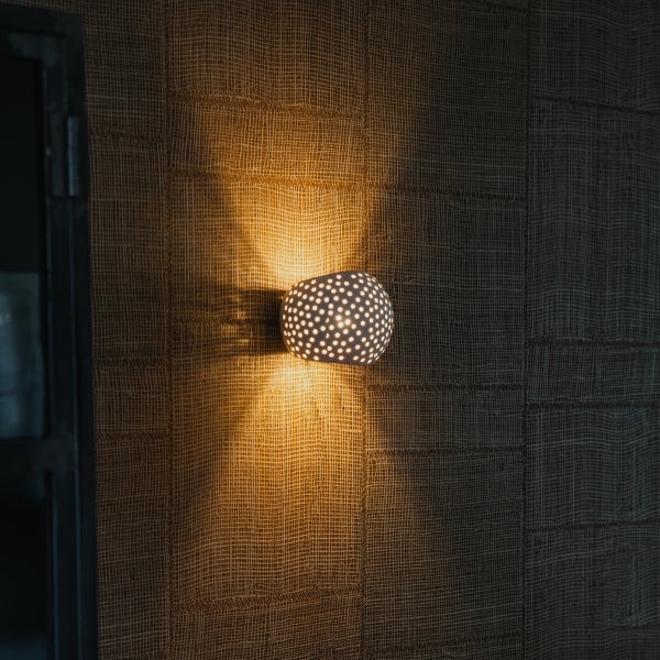 Wandleuchte mit Lochmuster an einer Wand