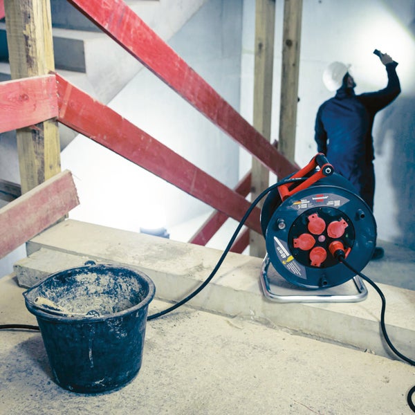 Baustellenszene mit Kabeltrommel, Eimer und Bauarbeiter mit Lampe