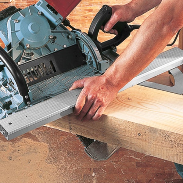 Handwerker verwendet eine Zimmererkreissäge zum Schneiden eines Holzbalkens auf einer Baustelle.