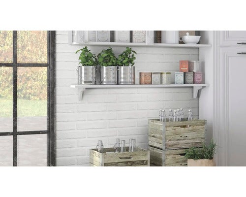 Wandregal in einer Küche mit weißer Backsteinwand, dekoriert mit Pflanzen in Metalltöpfen, Aufbewahrungsdosen und Holzkisten mit Glasflaschen.
