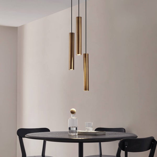 Drei Pendelleuchten aus Metall über einem Esstisch