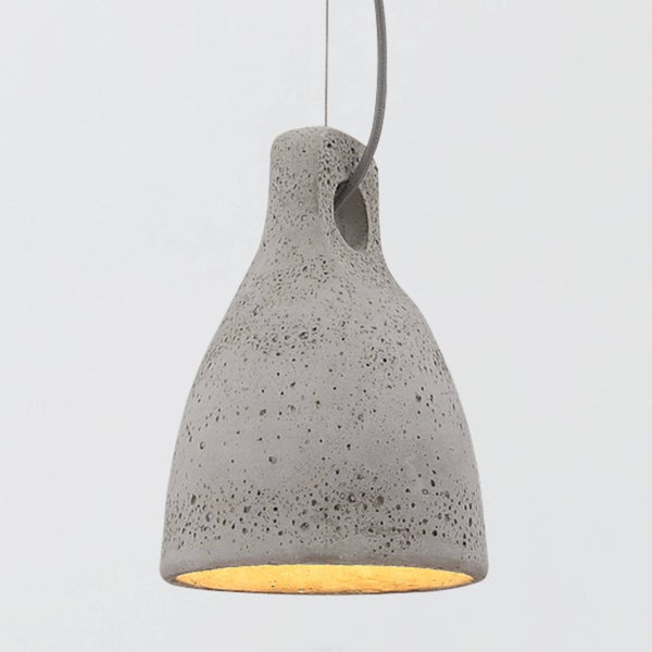 Pendelleuchte aus Beton in Glockenform mit poröser Oberfläche und warmem Lichtschein.