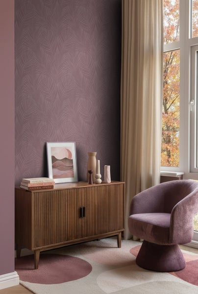 Vliestapete mit Palmblatt-Muster in Mauve, kombiniert mit einem Sideboard aus Holz, Samtsessel und gemustertem Teppich im modernen Wohnzimmer.