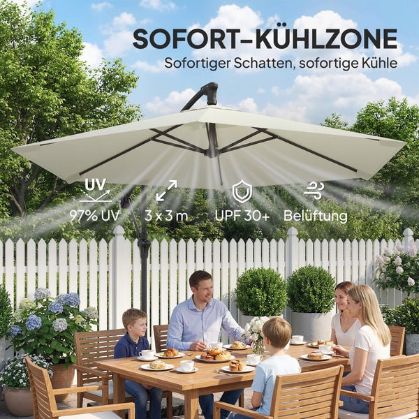 Ein cremefarbener Ampelschirm über einer grauen Gartenlounge aus Kunststoffgeflecht auf einer Steinterrasse vor einem Holzzaun.