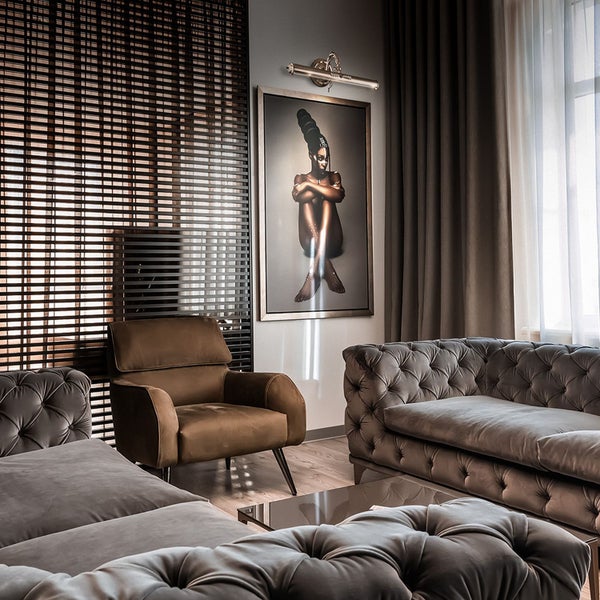 Wohnzimmer mit Sofa, Sessel, Jalousien und einem gerahmten Bild