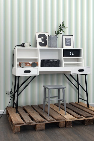 Weißer Schreibtisch mit Aufbewahrungselementen, schwarzem Metallgestell und grauem Hocker auf Holzpaletten