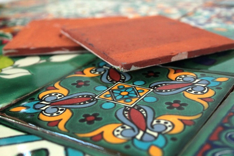 Detailansicht eines Waschbeckens aus Kupfer mit Wasserhahn vor einer Wand mit verzierten Fliesen.