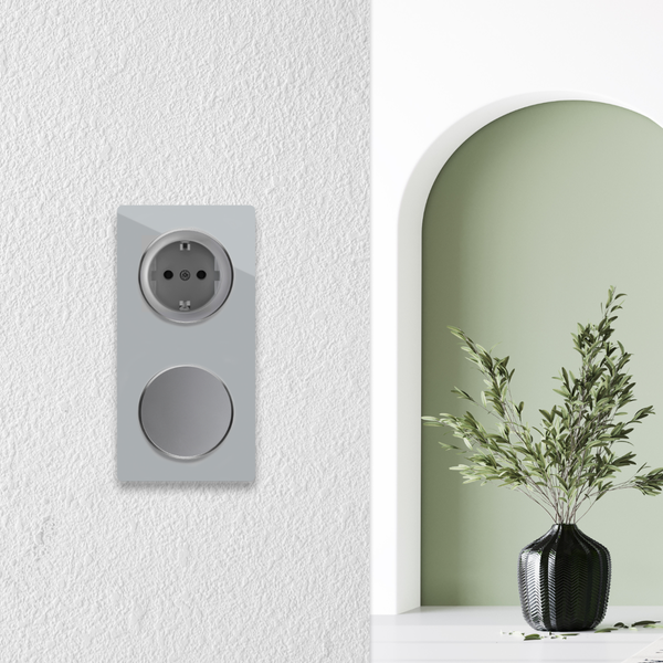 Eine Kombination aus Steckdose und Lichtschalter an einer Wand neben einem torbogenartigen Durchgang mit einer dekorativen Pflanze in einer Vase.