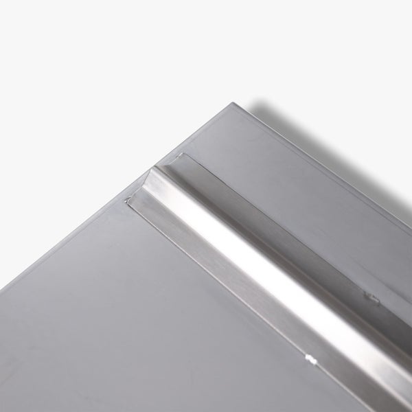 Detailansicht einer Edelstahlplatte mit einem aufgeschweißten Metallprofil und sichtbaren Schweißstellen.