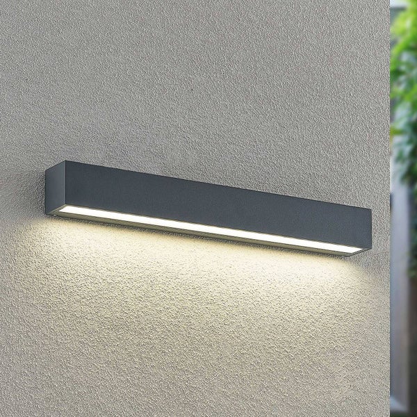 Moderne rechteckige LED-Außenwandleuchte in Anthrazit, an einer Wand montiert, mit warmweißem Lichtschein nach unten.