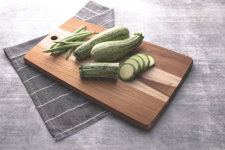Rechteckiges Holzschneidebrett von Tramontina mit Zucchini und grünen Bohnen auf einem Küchentuch.